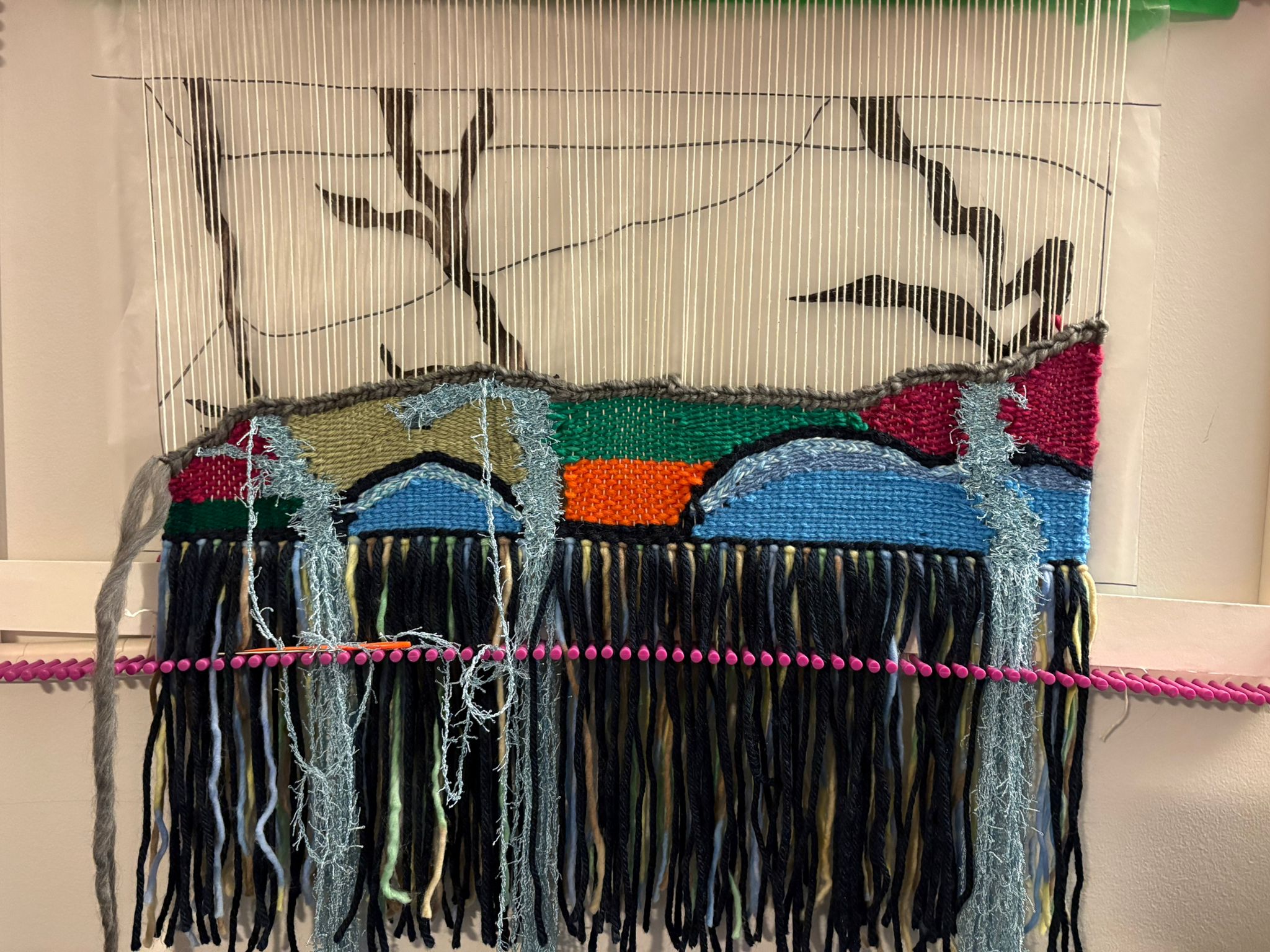 Early stages of the weaving showing colorful fibers being woven