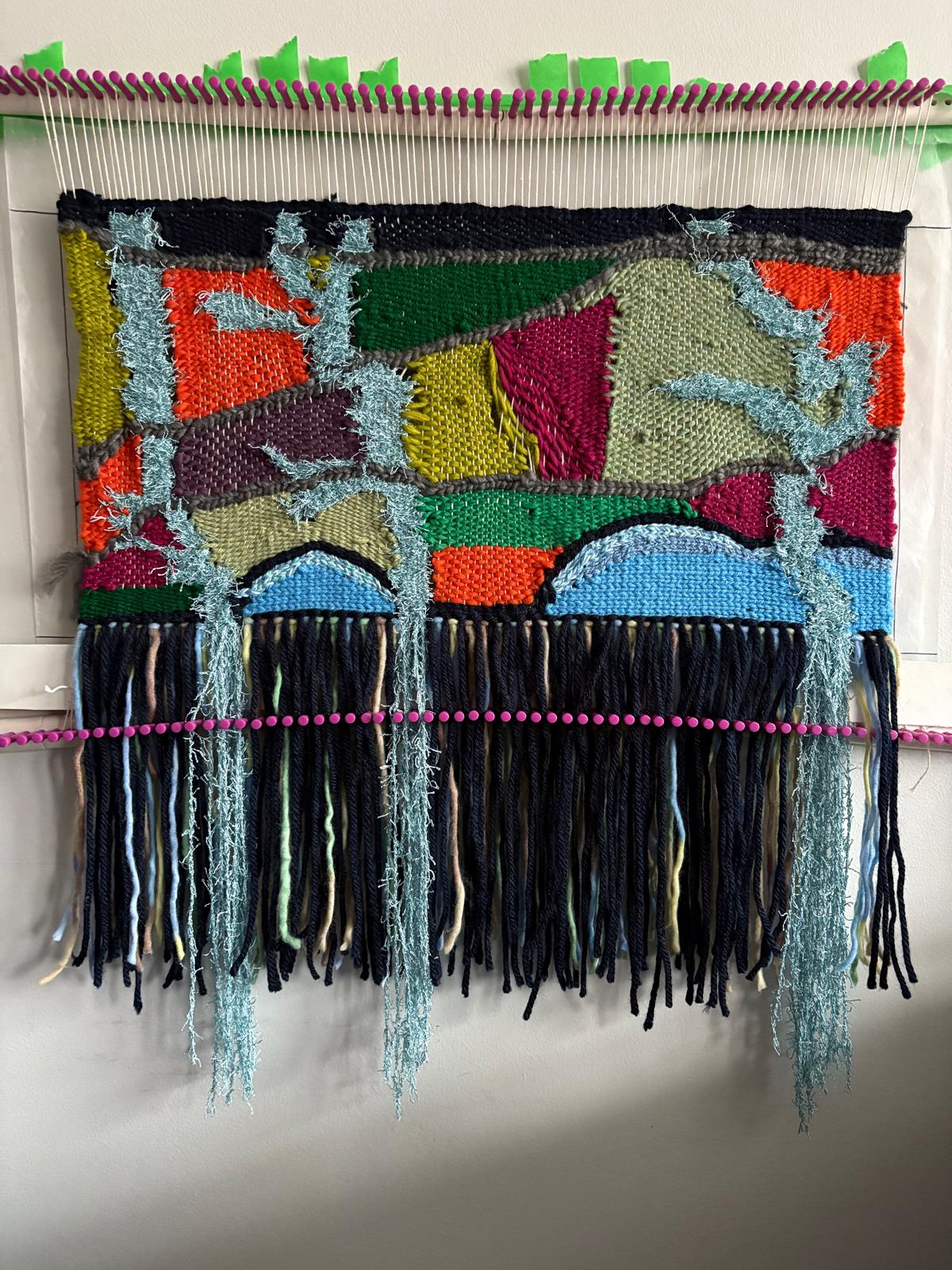 The weaving taking shape on the loom, showing the full composition